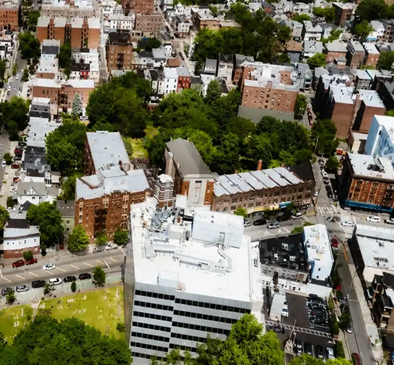 Aerial view of an urban area with mixed residential buildings, greenery, and streets.